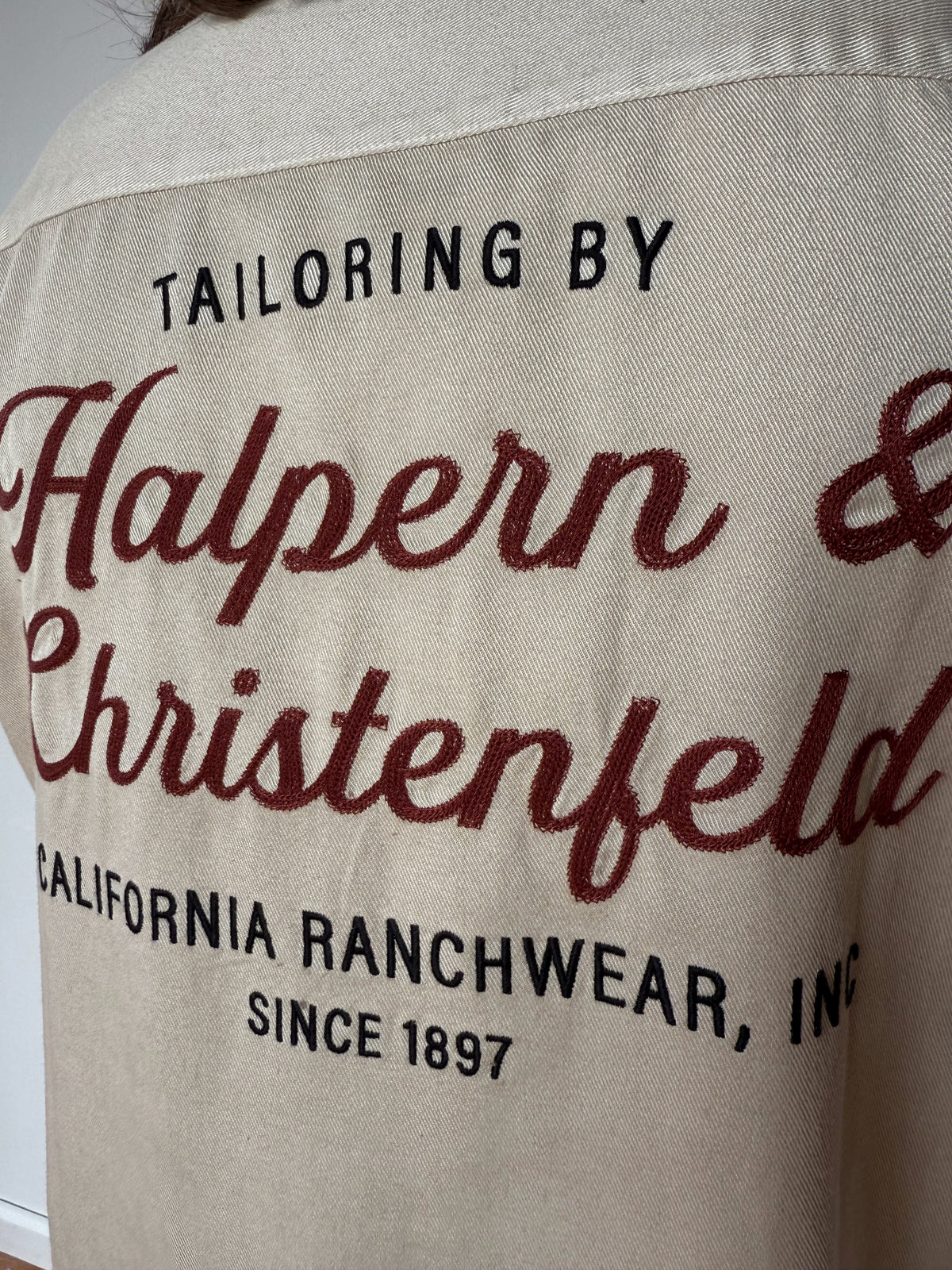 Close-up of the Tailoring by Halpern & Christenfeld back print on the cream H Bar C heritage bowling shirt.
