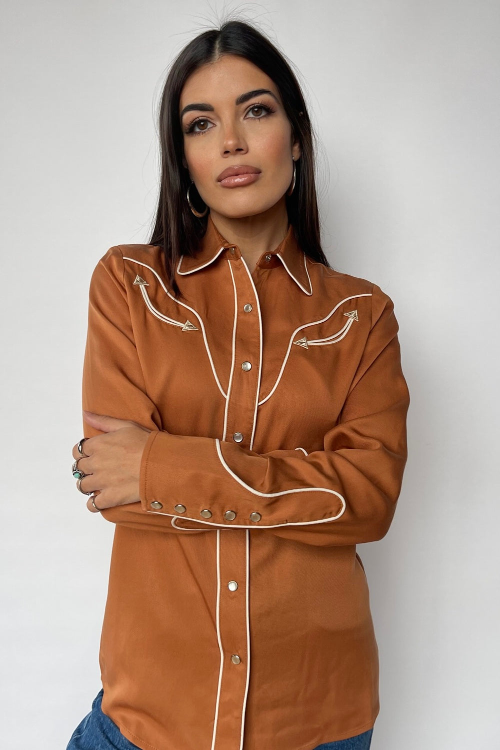 Woman wearing the H Bar C San Fernando women's shirt in burnt orange with cream piping and arrow details.