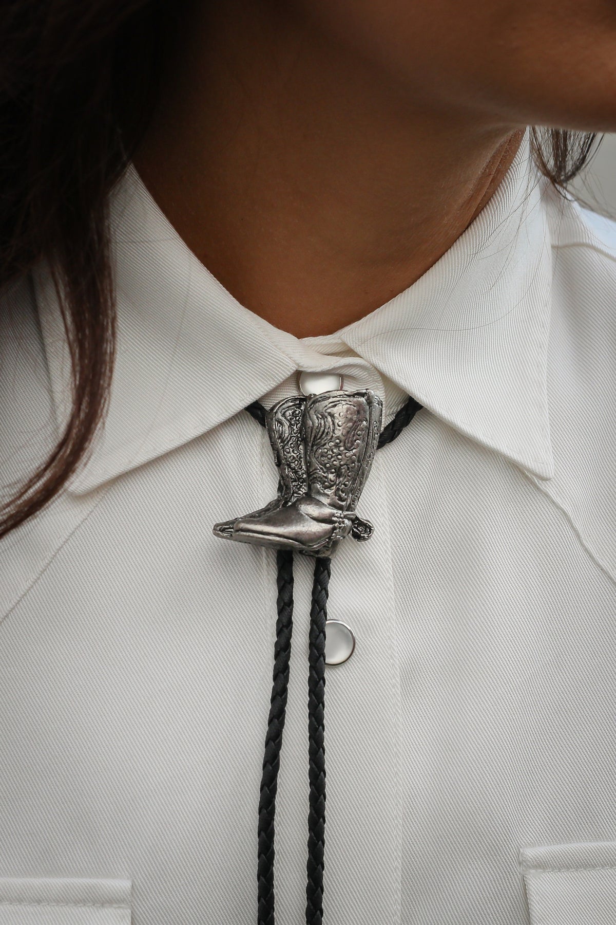H Bar C cowboy boots bolo tie with silver boot slide and braided leather cord worn on a white shirt, from Five Pieces of the Frontier.
