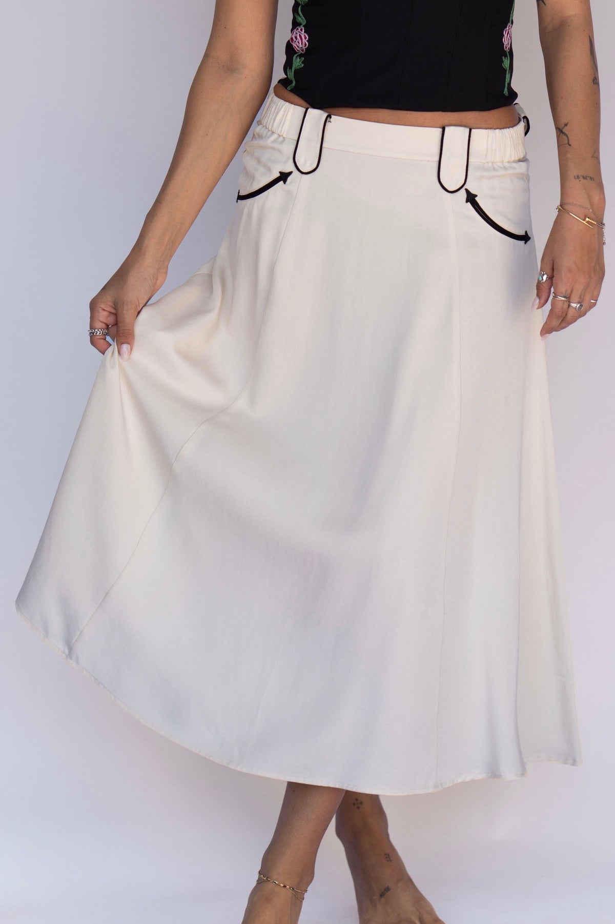 Close-up of the full swing of the H Bar C Santa Fe off white skirt with black piped pockets.