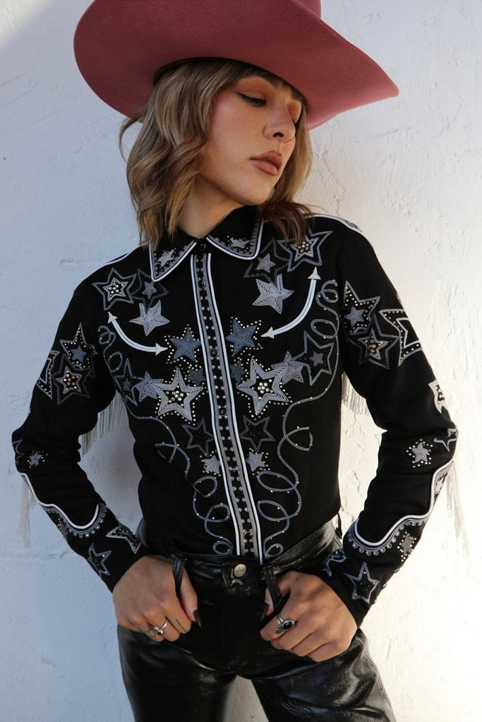 Woman in a pink cowboy hat wearing the H Bar C Las Vegas women's shirt in black with chain stitch stars and rhinestones.