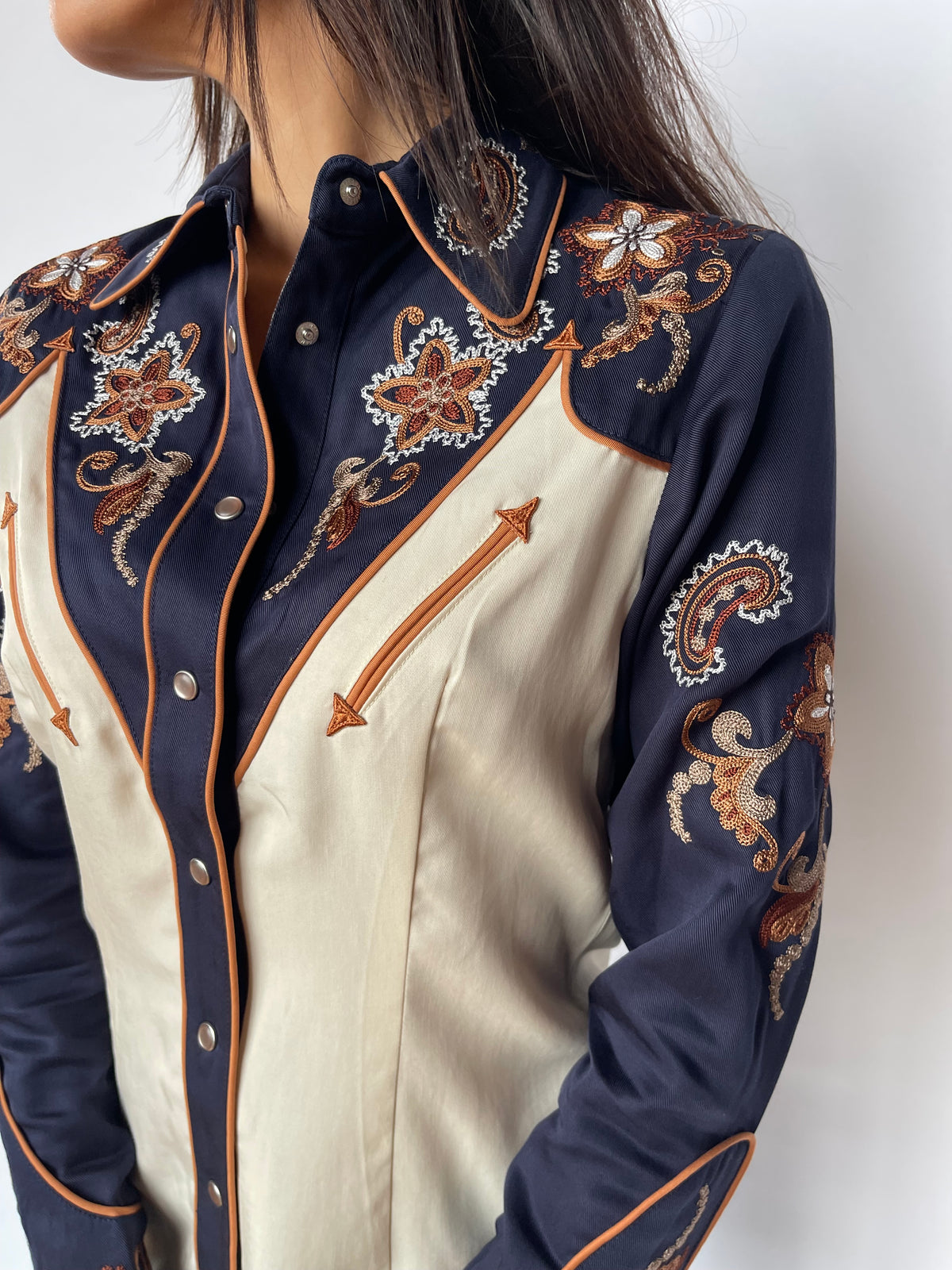 Close-up of the floral embroidery, arrow pocket, and piping on the H Bar C Aspen off white and navy women's western shirt.