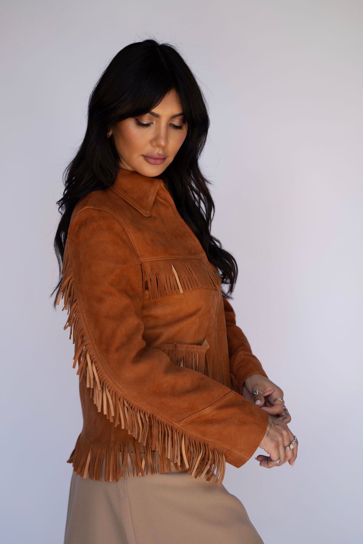 Model in the H Bar C Omaha brown suede fringe jacket and a beige mini skirt.