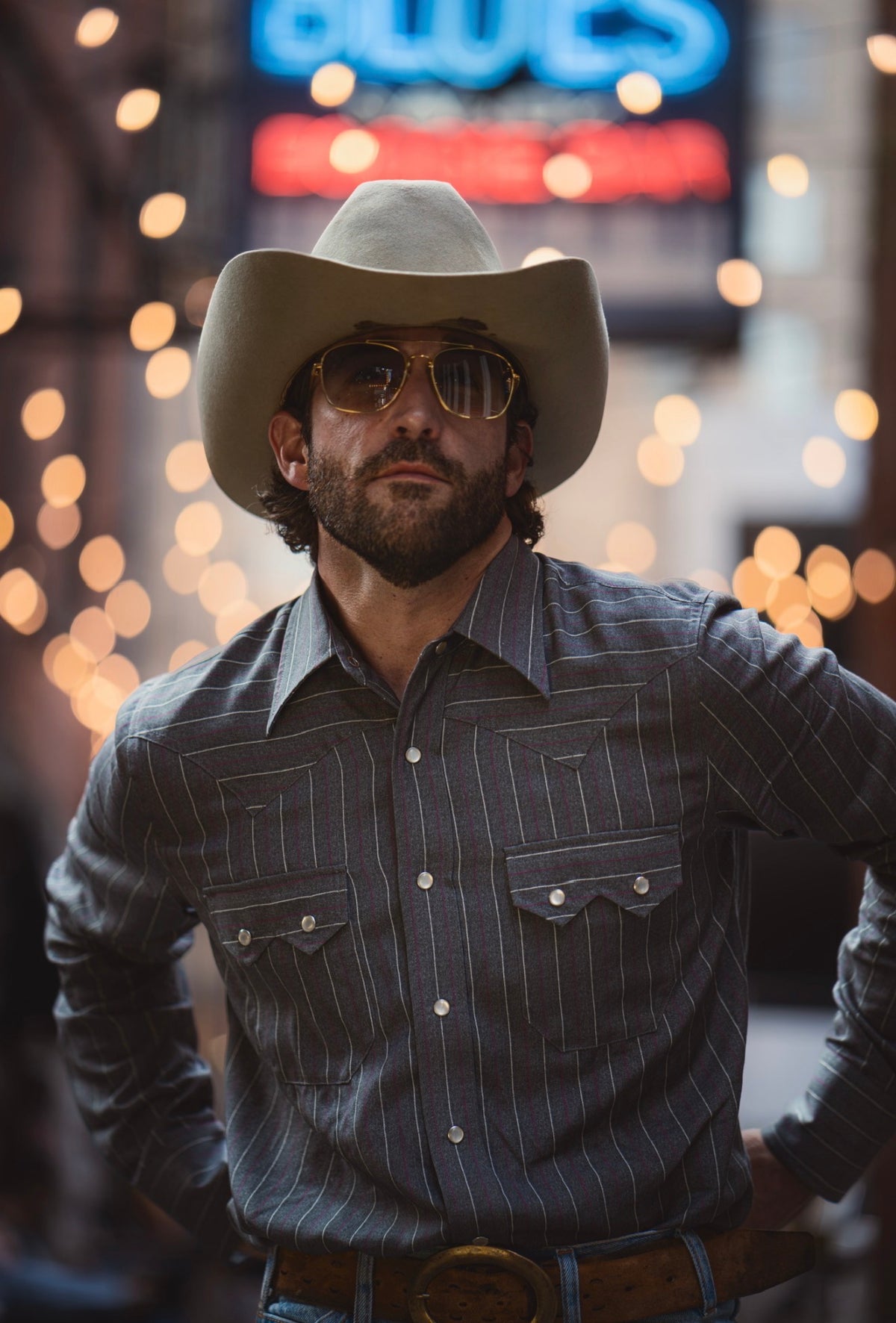 Man in a cowboy hat at night under neon lights wearing the H Bar C Tiger western shirt, a 1940s H Bar C remake.