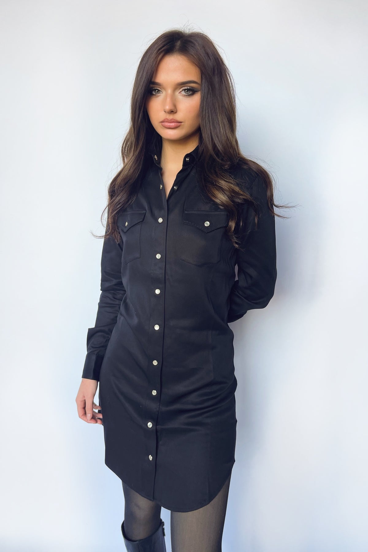Woman wearing the H Bar C Savannah women's black shirt dress with pearl snaps and sheer black tights.