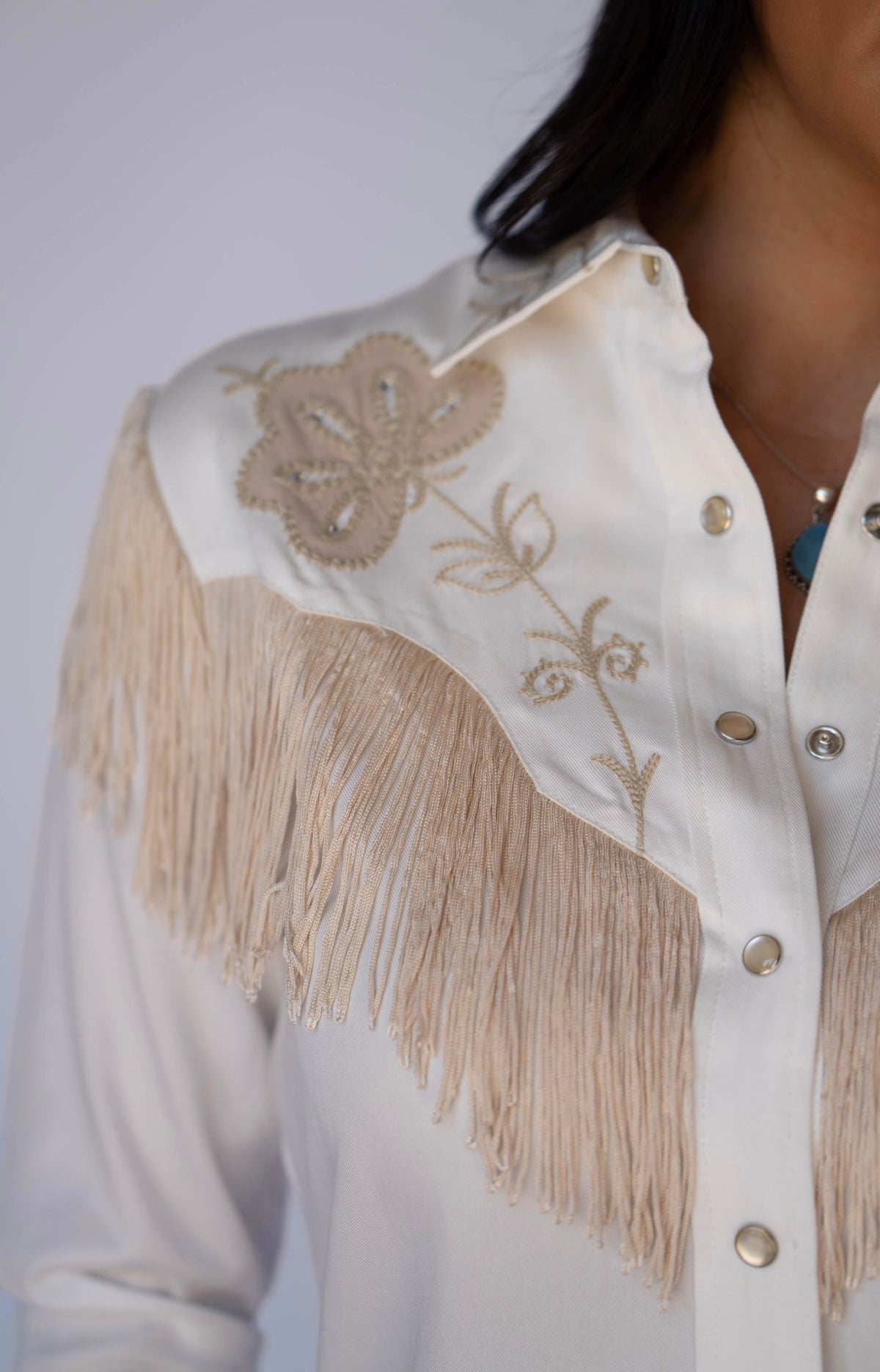 Close-up of the embroidered floral yoke and beige fringe on the H Bar C Roswell white dress.