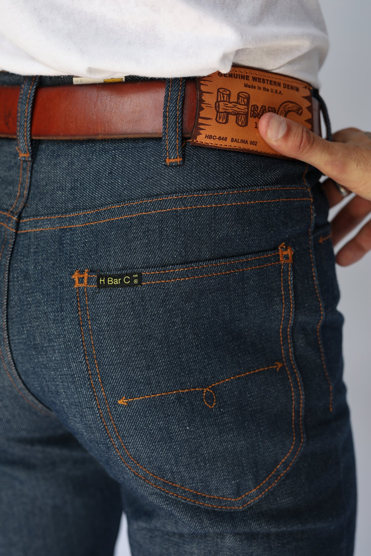 Back pocket detail of the H Bar C Boot Cut Flare indigo jeans with a tooled leather belt.