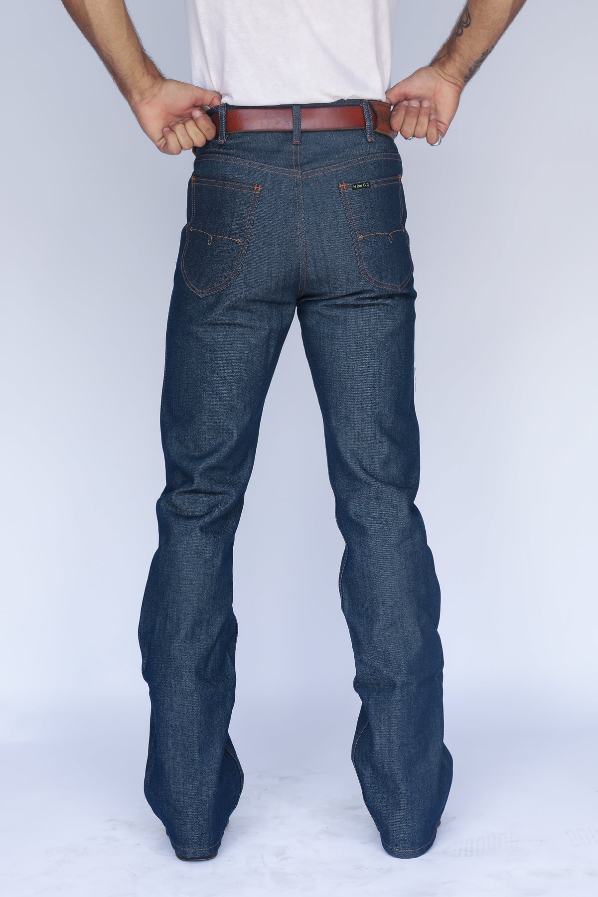 Back view of the H Bar C Boot Cut Flare indigo jeans showing the fit and flare over boots.