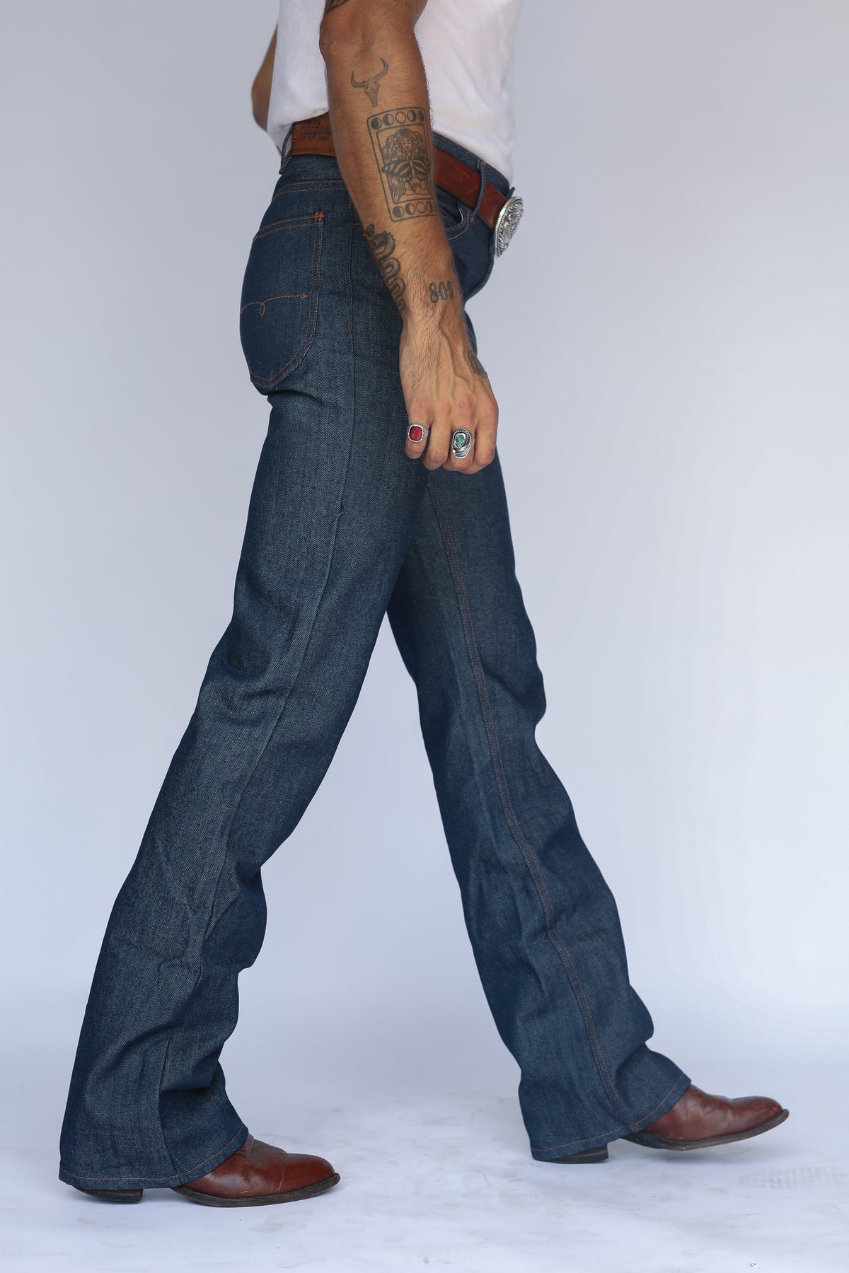Side stride view of the H Bar C Boot Cut Flare indigo jeans over brown cowboy boots.