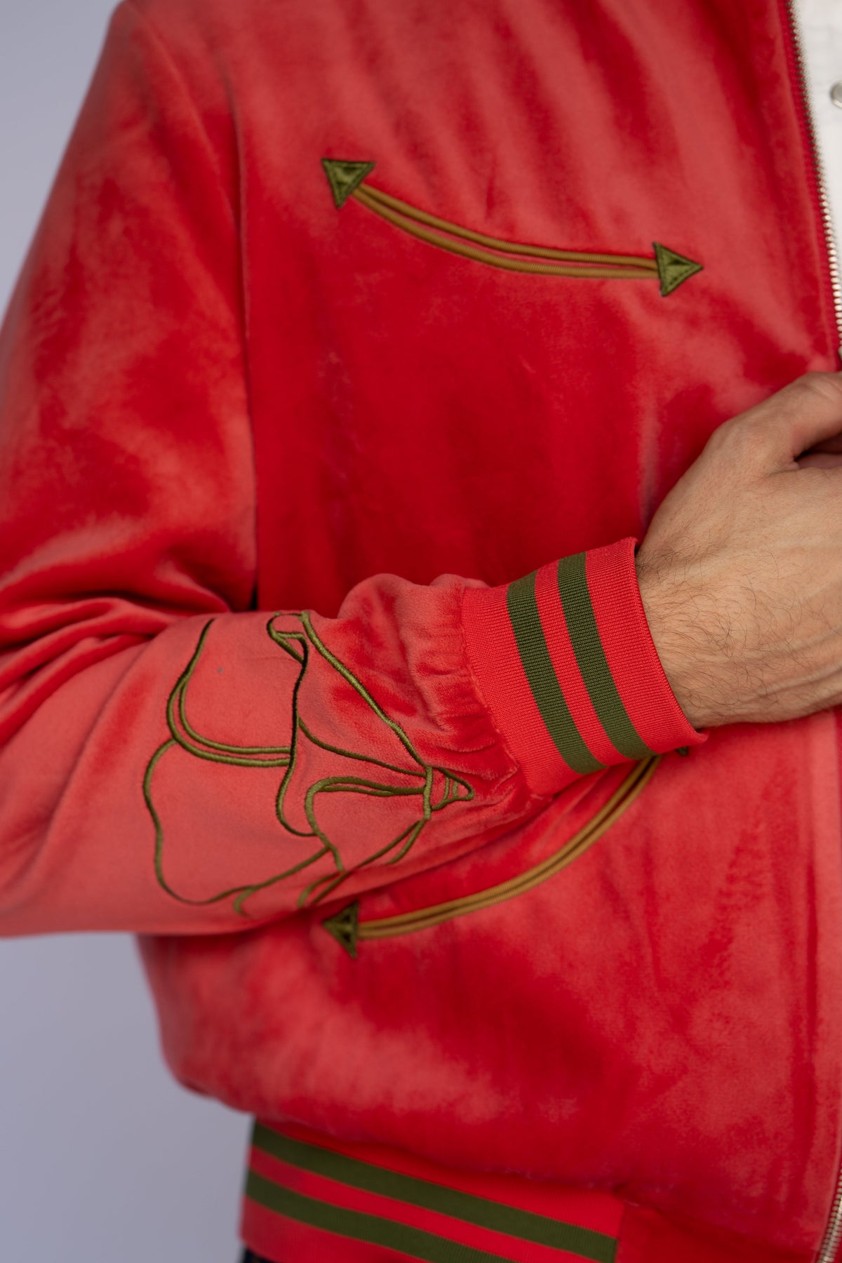 Sleeve detail of the HBarC x Gibson Dove red tour jacket with embroidered arrow, poppy outline, and striped cuff.