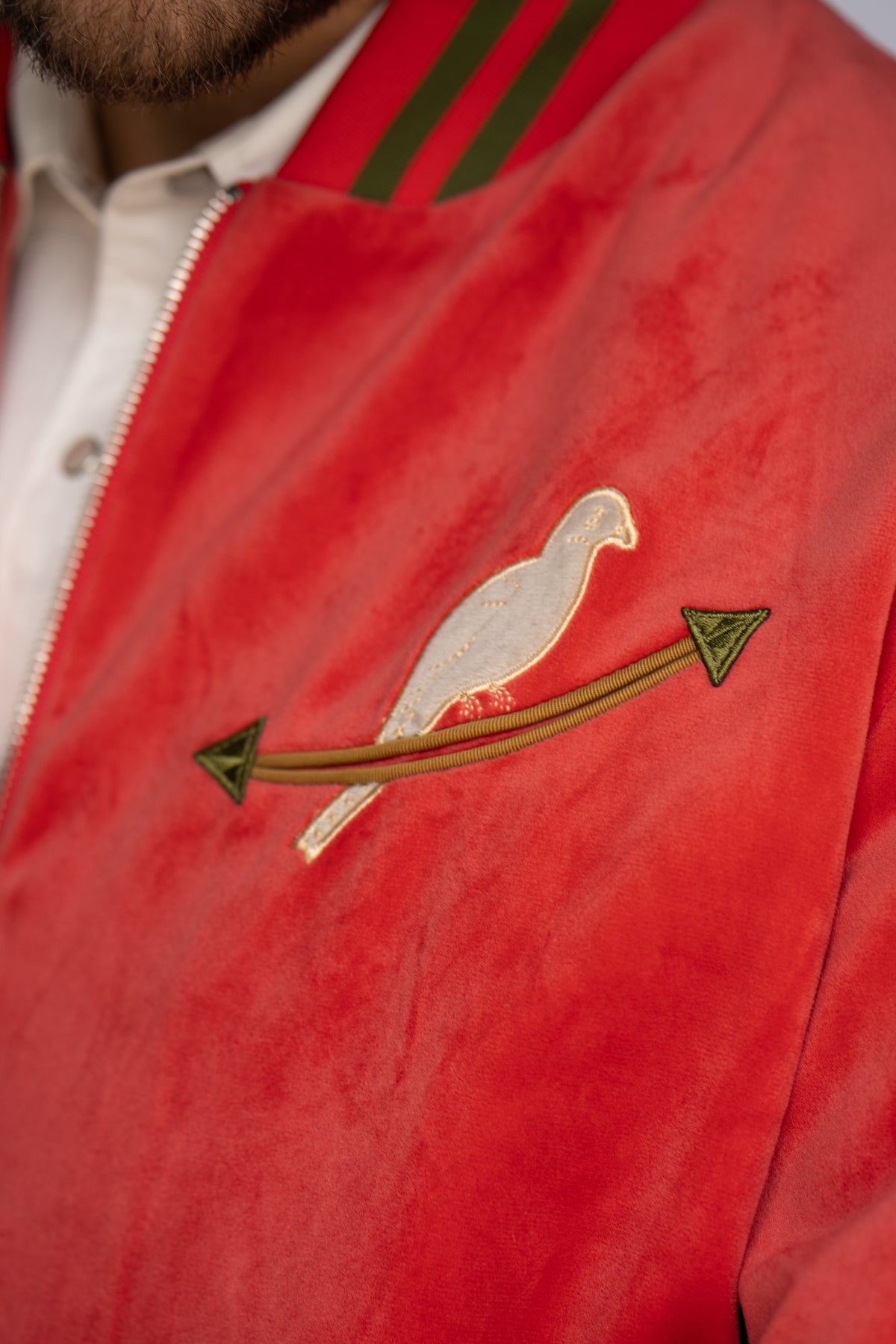 Chest close-up of the dove and arrow embroidery on the HBarC x Gibson Dove unisex red tour jacket.