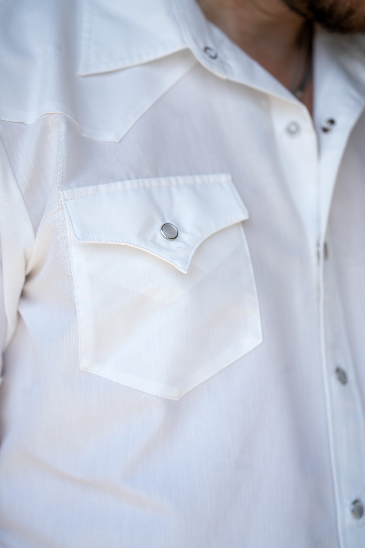 Close-up of the horse jacquard fabric, pocket, and pearl snap on the H Bar C Newport Jacquard shirt.
