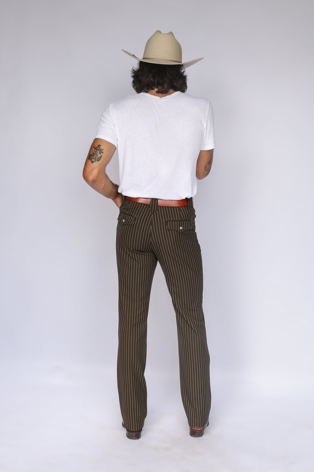 Full back view of a man in a cowboy hat wearing the H Bar C Bakersfield brown pinstripe western pants.