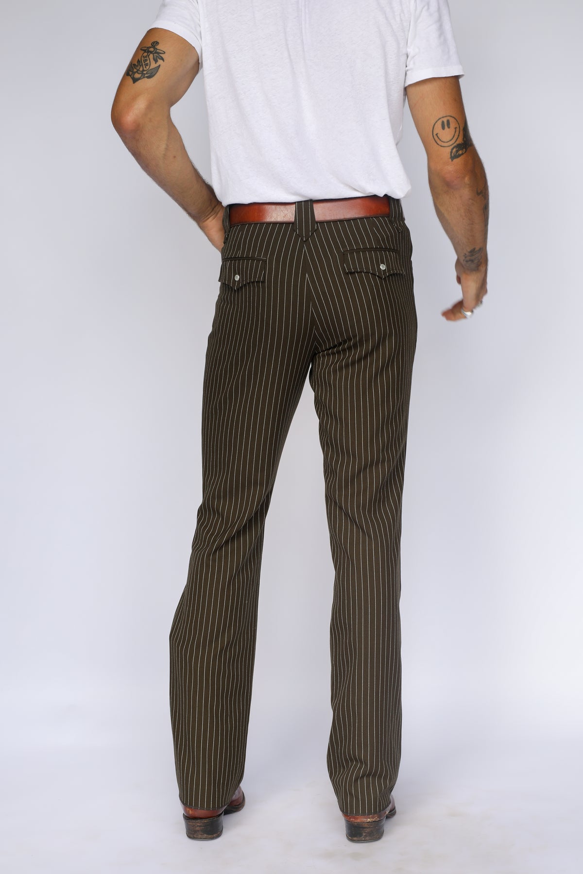 Three-quarter back view of the H Bar C Bakersfield brown pin stripe pants worn with a white tee.