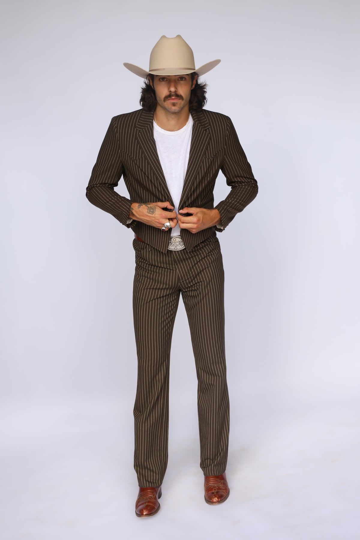 Man buttoning the H Bar C Bakersfield brown pin stripe western jacket with matching pants and cowboy hat.