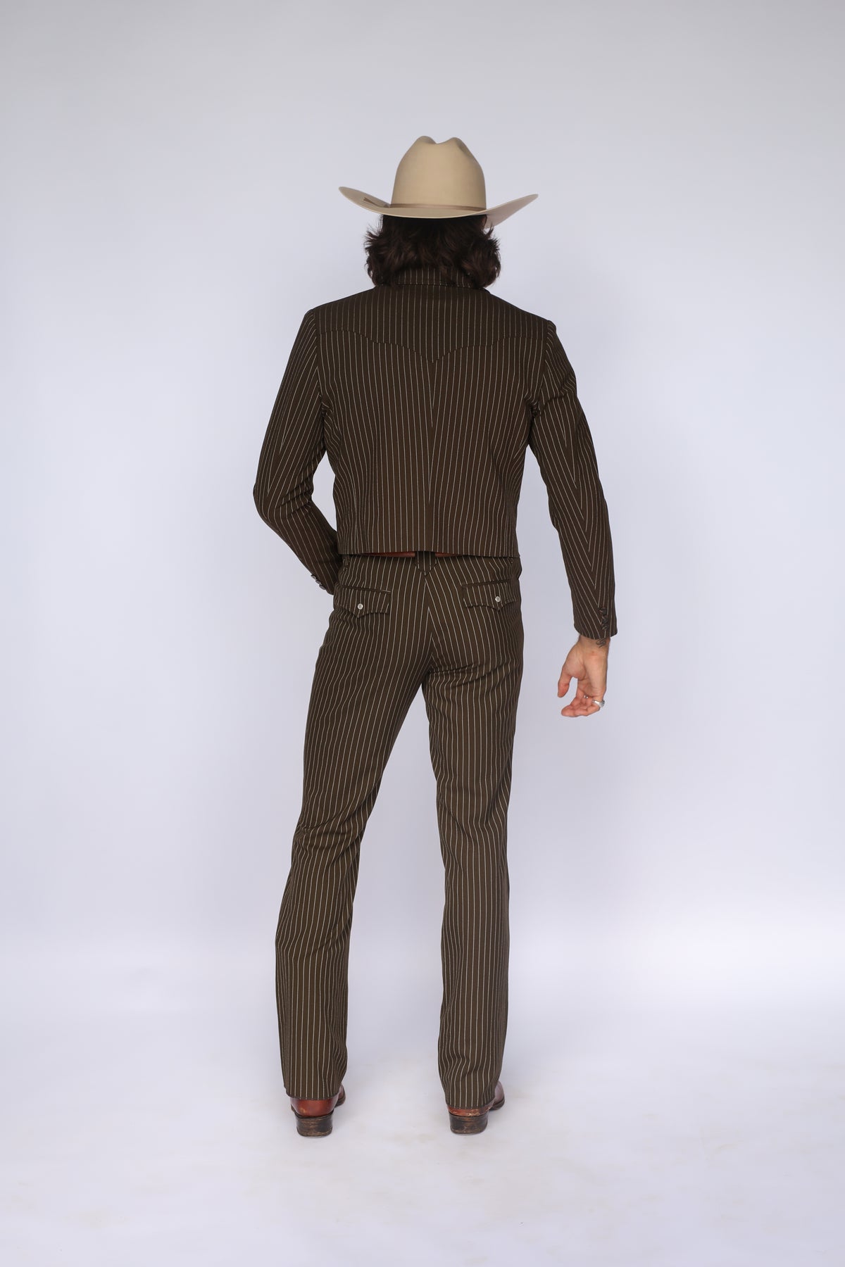 Back view of the H Bar C Bakersfield brown pinstripe jacket and pants worn as a western suit with a cowboy hat.