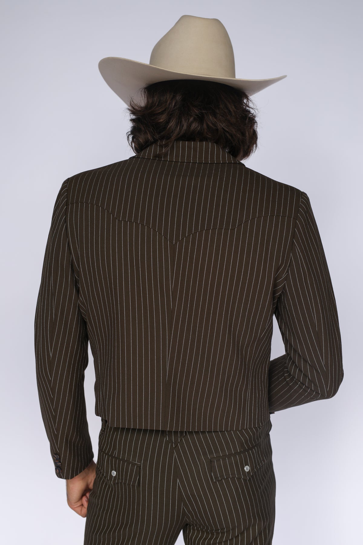 Back shoulder detail of the H Bar C Bakersfield brown pin stripe western jacket with a cream cowboy hat.