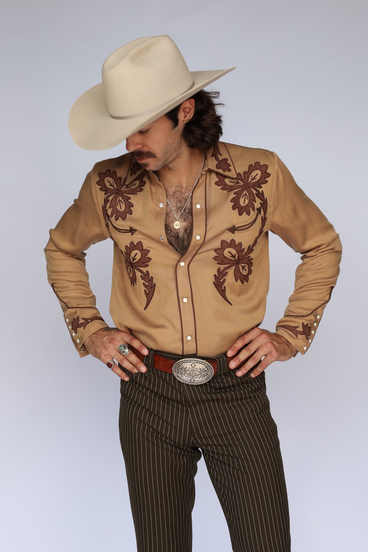 Front view of the H Bar C Terlingua tan embroidered western shirt with a silver buckle and cowboy hat.