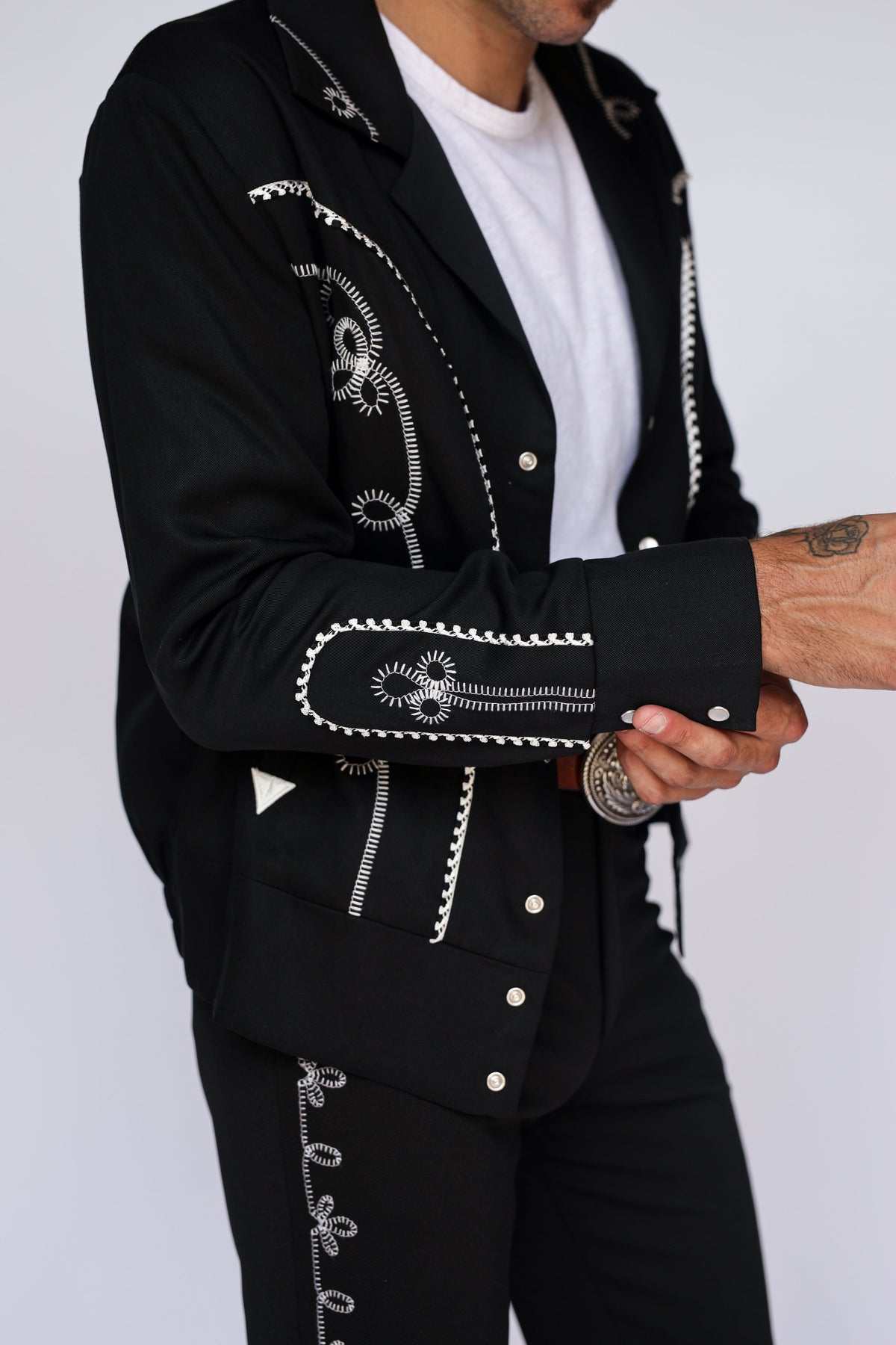 Cuff and sleeve detail of the H Bar C Bolero black and white western jacket, showing white chain stitch embroidery and the matching Bolero pants.