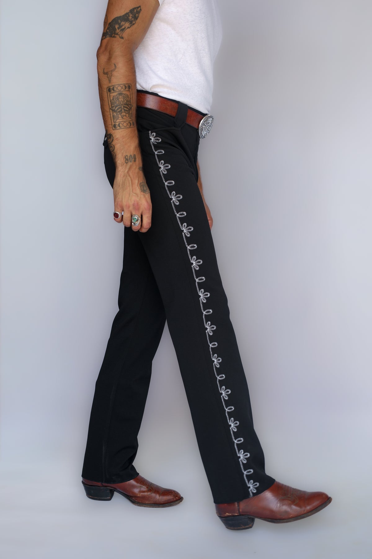 Walking side view of the H Bar C Bolero pants in black with white embroidered side seam, inspired by the 1936 Bob Wills Bolero.
