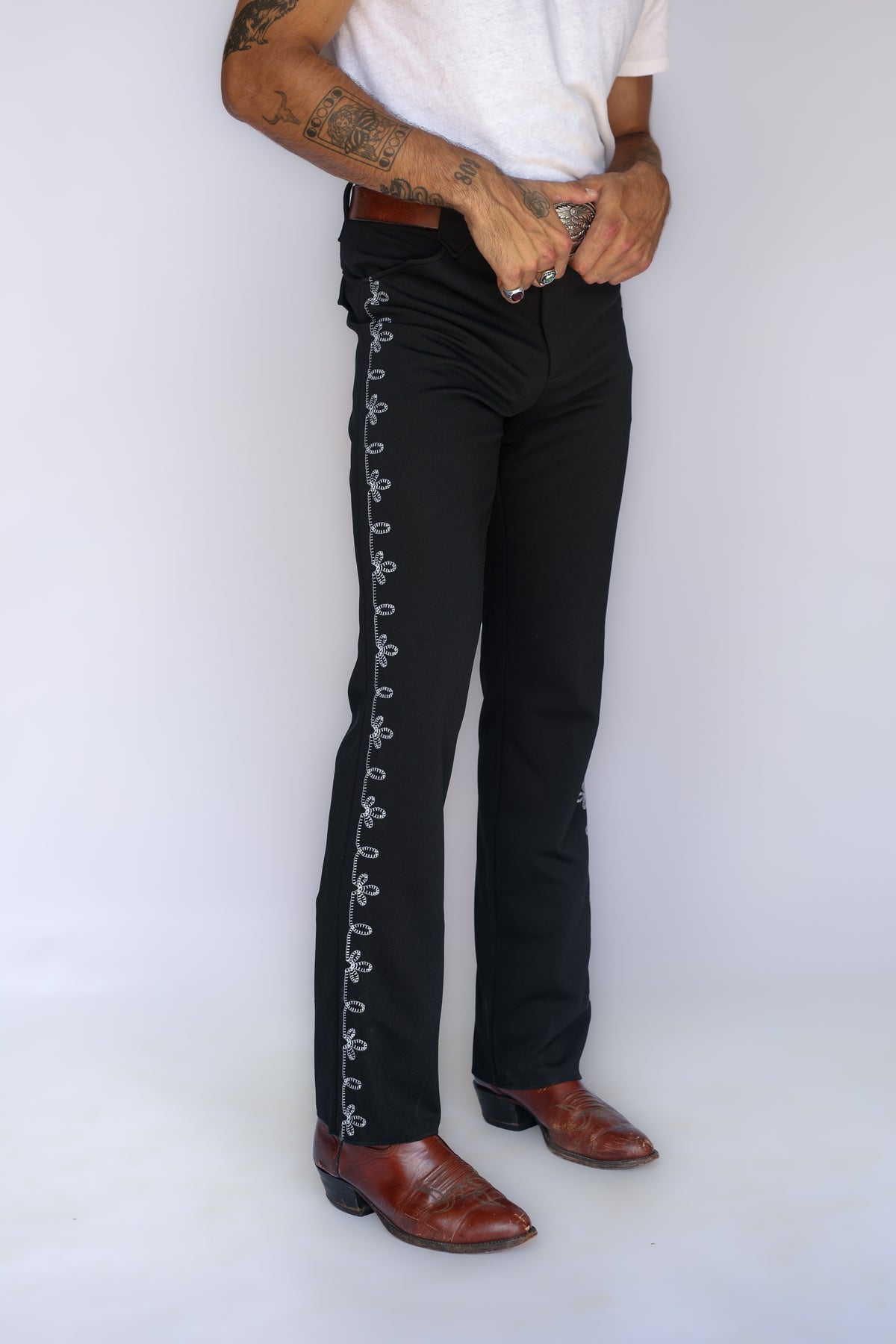 Close-up of the white horseshoe and chain stitch embroidery running down the side of the H Bar C Bolero black pants.