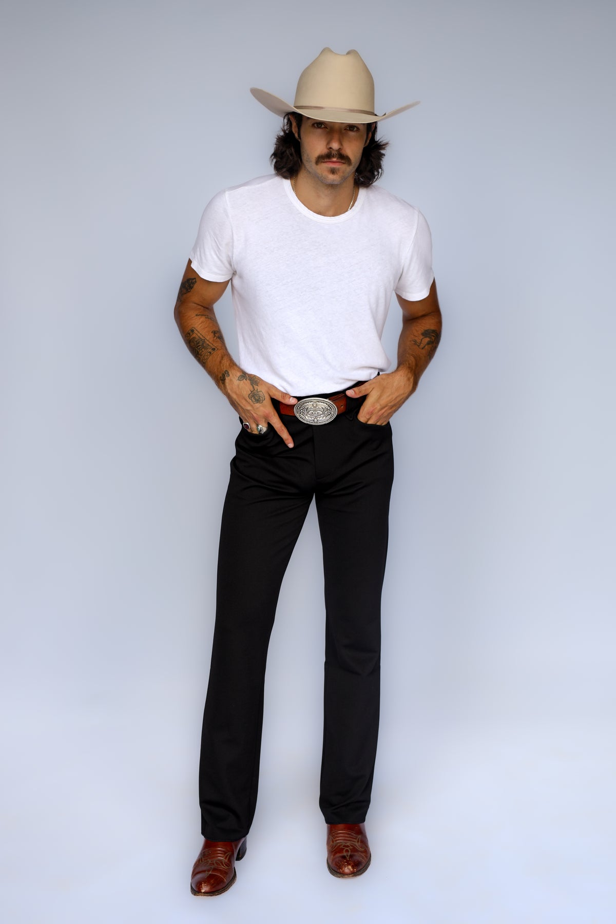 Front view of the H Bar C Franklin black stretch western pants styled with a white tee, buckle, and cream cowboy hat.