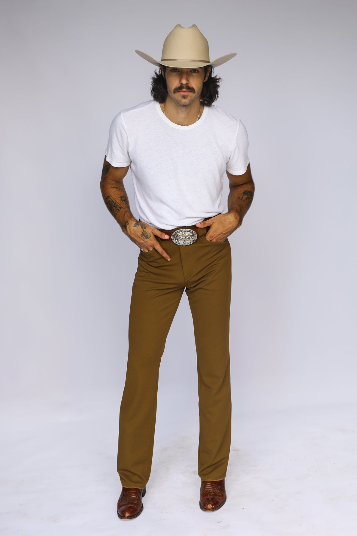 Full length view of the H Bar C Franklin unisex olive pants with a white tee and cream hat.