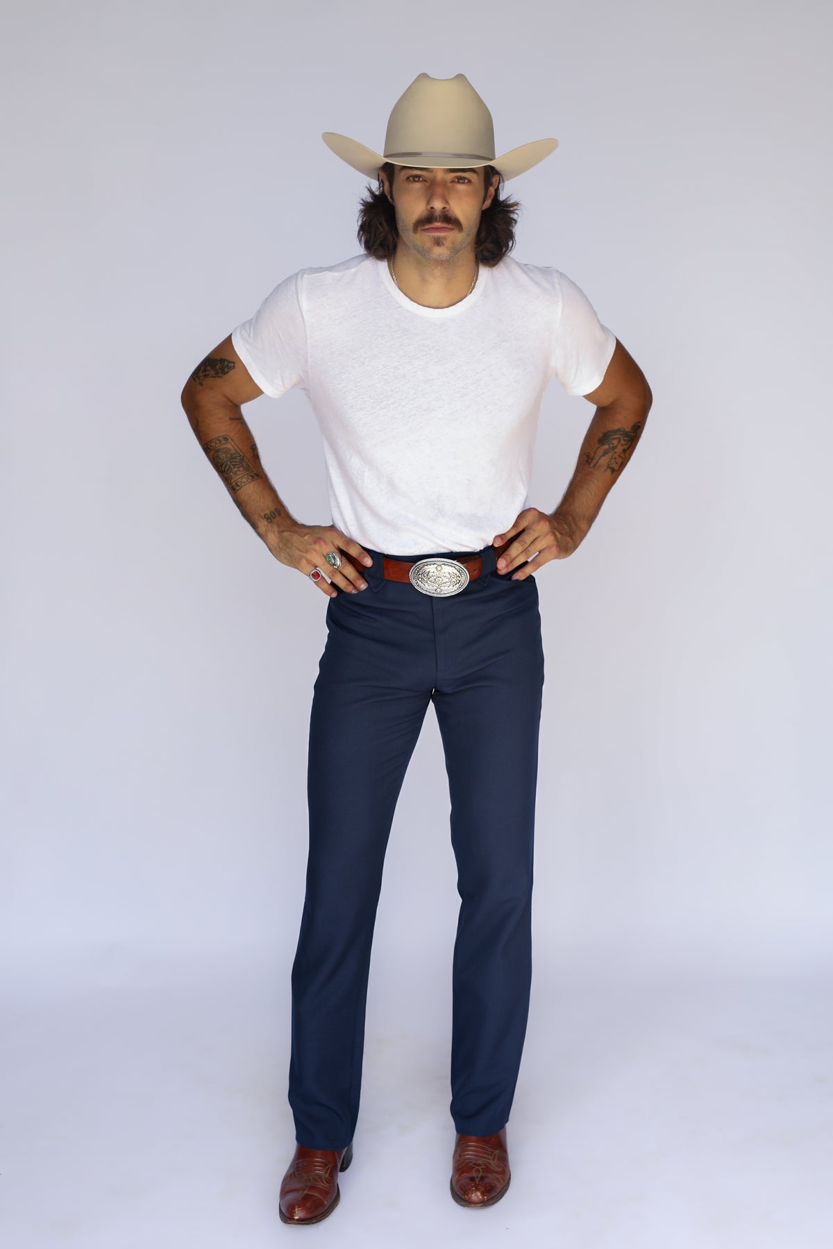 Full length view of a man in a cream cowboy hat wearing the H Bar C Franklin navy unisex western pants.