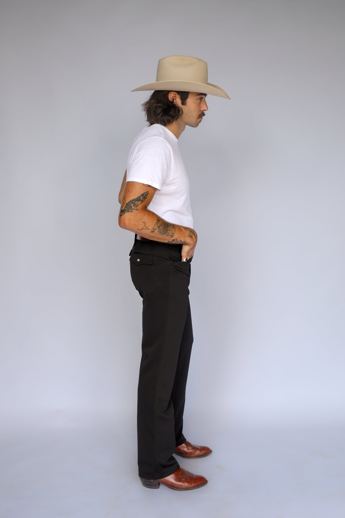 Side view of a man in a cowboy hat wearing the H Bar C Franklin black western pants with a white tee and boots.