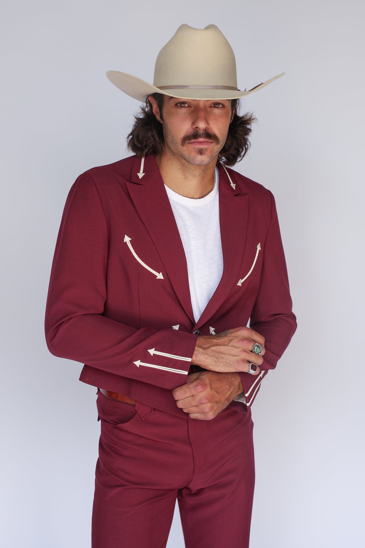 Man in a cream cowboy hat wearing the H Bar C Calamity men's maroon jacket with cream arrow lapel details.