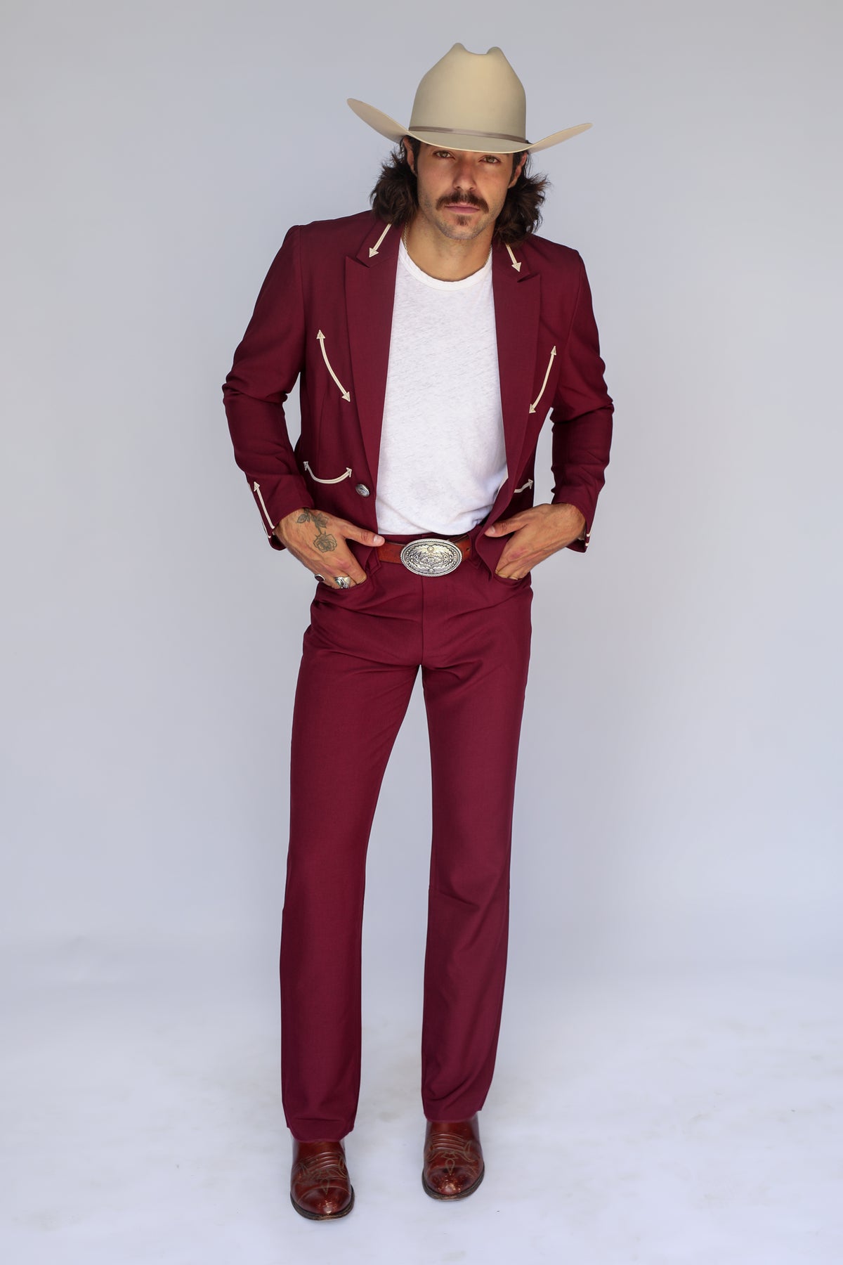 Front view of the H Bar C Calamity maroon suit with cream arrow details, silver buckle, and cowboy hat.