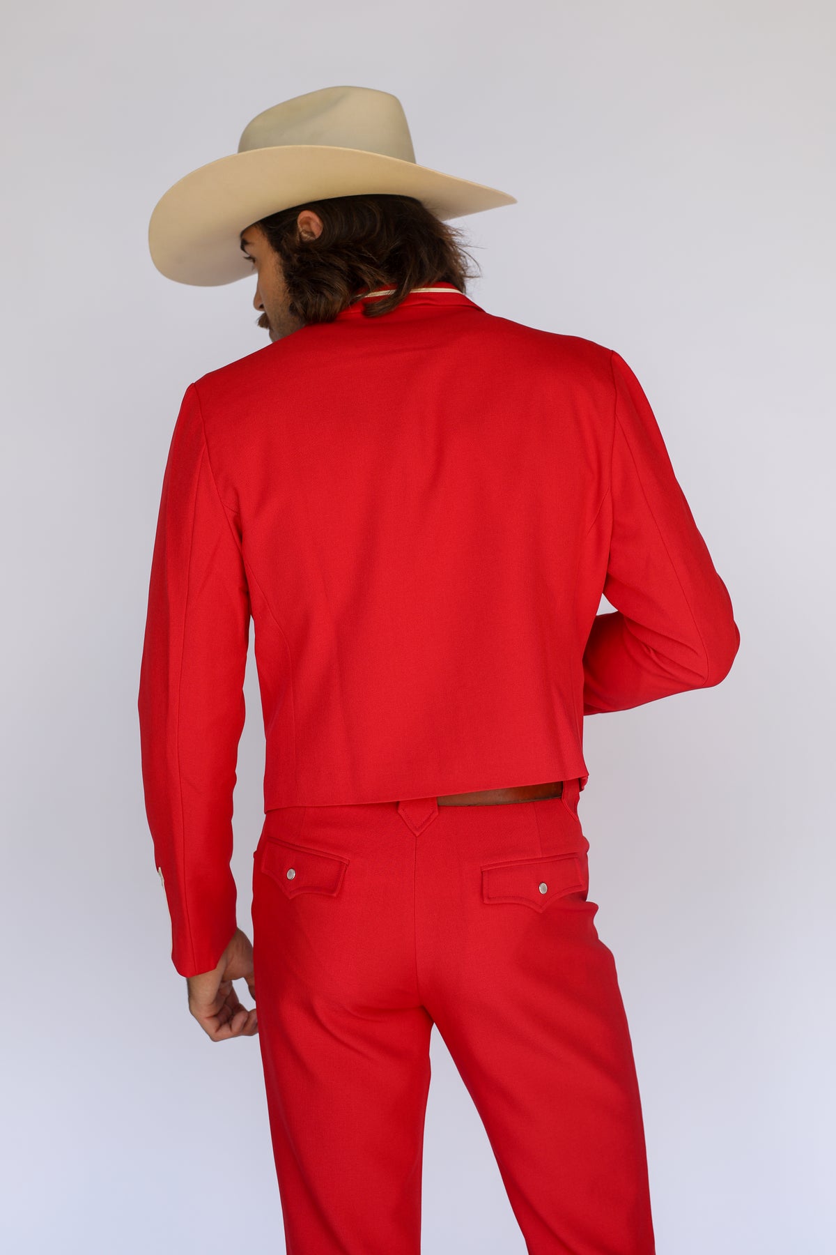 Back view of the H Bar C Calamity men's red cropped jacket with a cream cowboy hat.