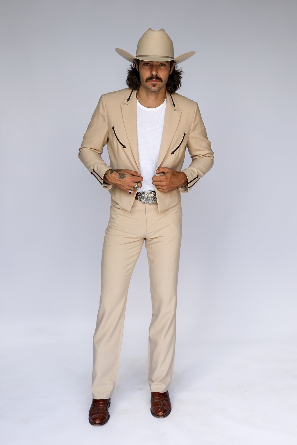 Man in a cream cowboy hat wearing the H Bar C Calamity tan jacket and matching tan western pants as a suit.