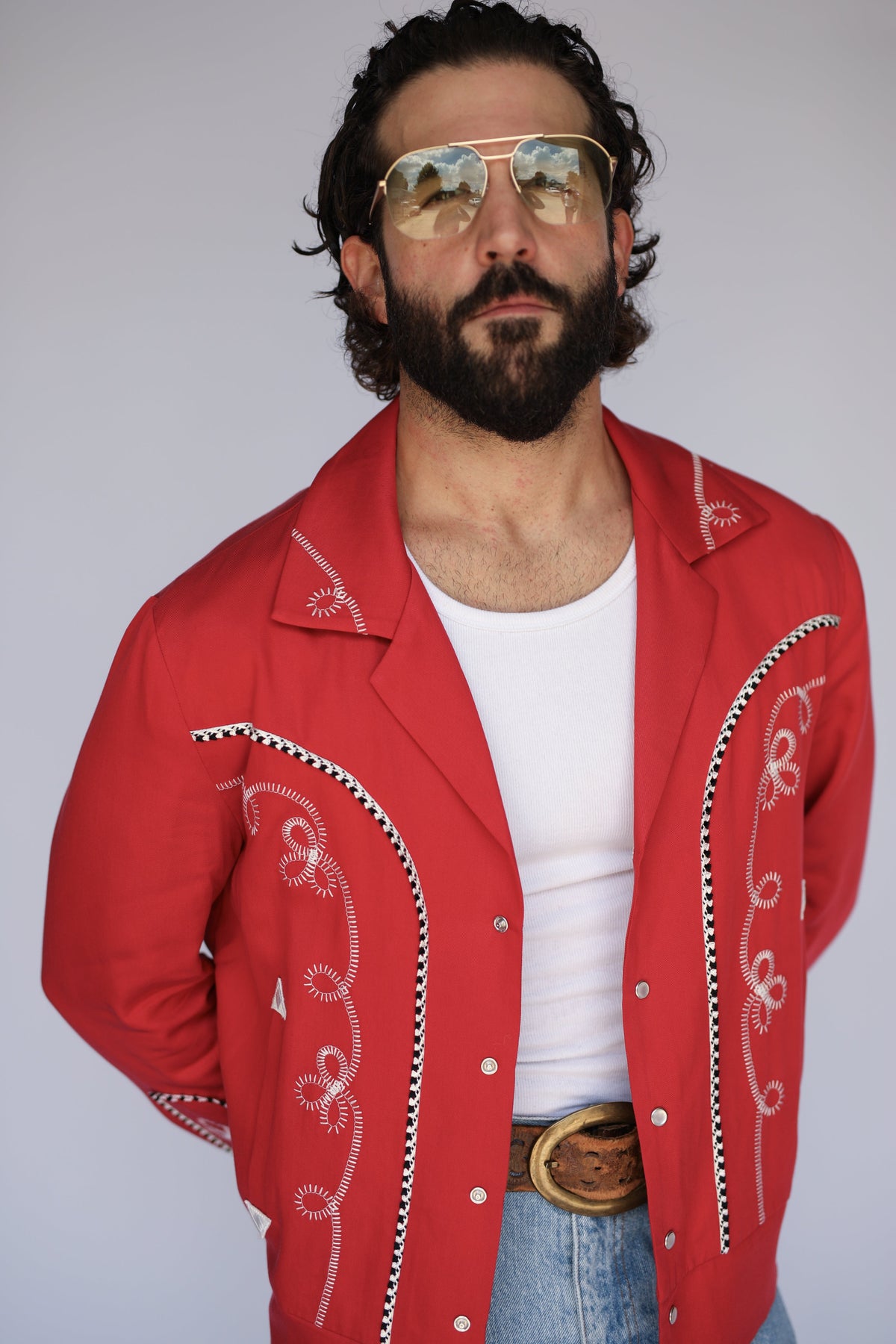 Close-up of the white scrollwork embroidery and horseshoe appliqué on the H Bar C Bolero men's red jacket.