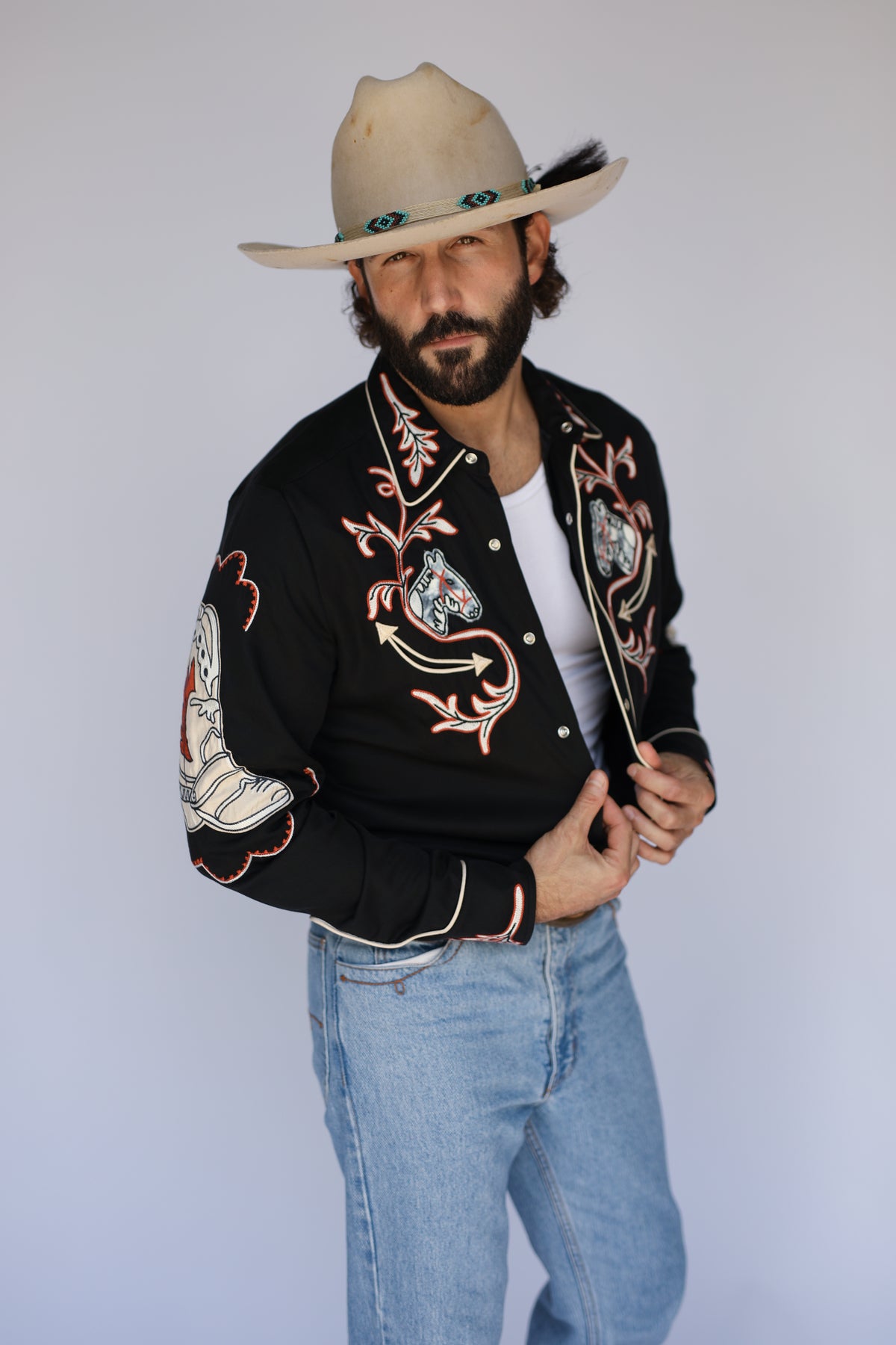 Man wearing the H Bar C Calabasas black shirt with chain stitch horse heads and cowboy boot sleeves.