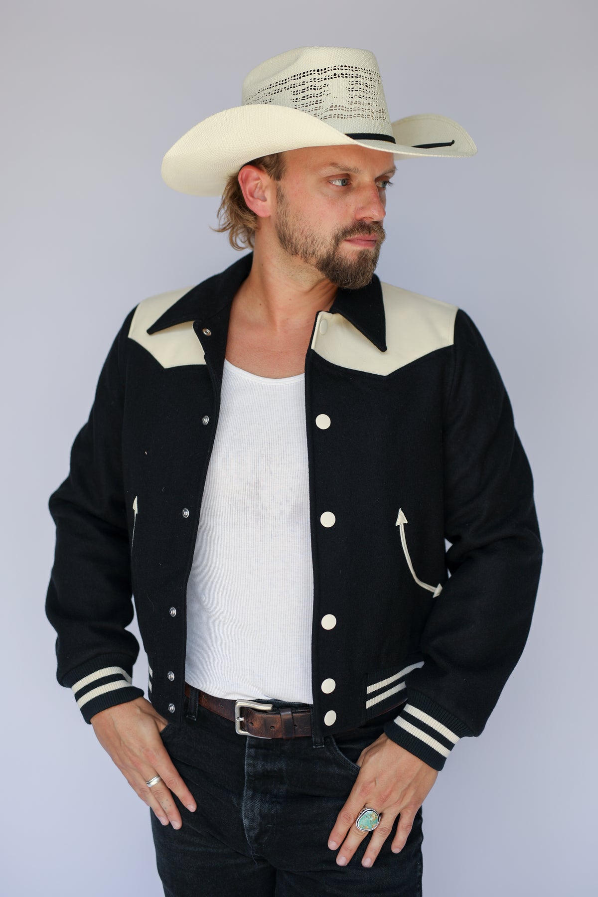 Man with hand in pocket wearing The Vail H Bar C black and cream western jacket.