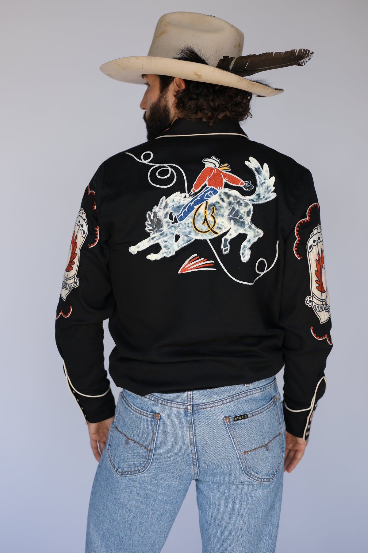 Back of the H Bar C Calabasas black shirt with a chain stitch cowboy riding a bucking bronco.