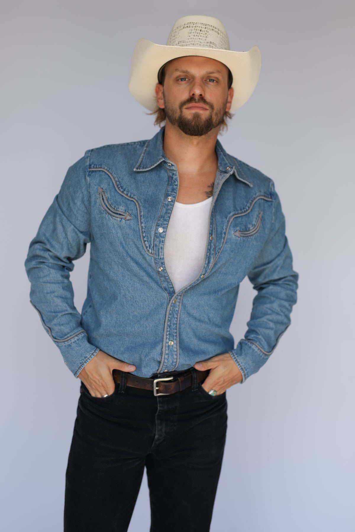 Front view of the H Bar C San Fernando light wash denim snap shirt with black jeans and a leather belt.