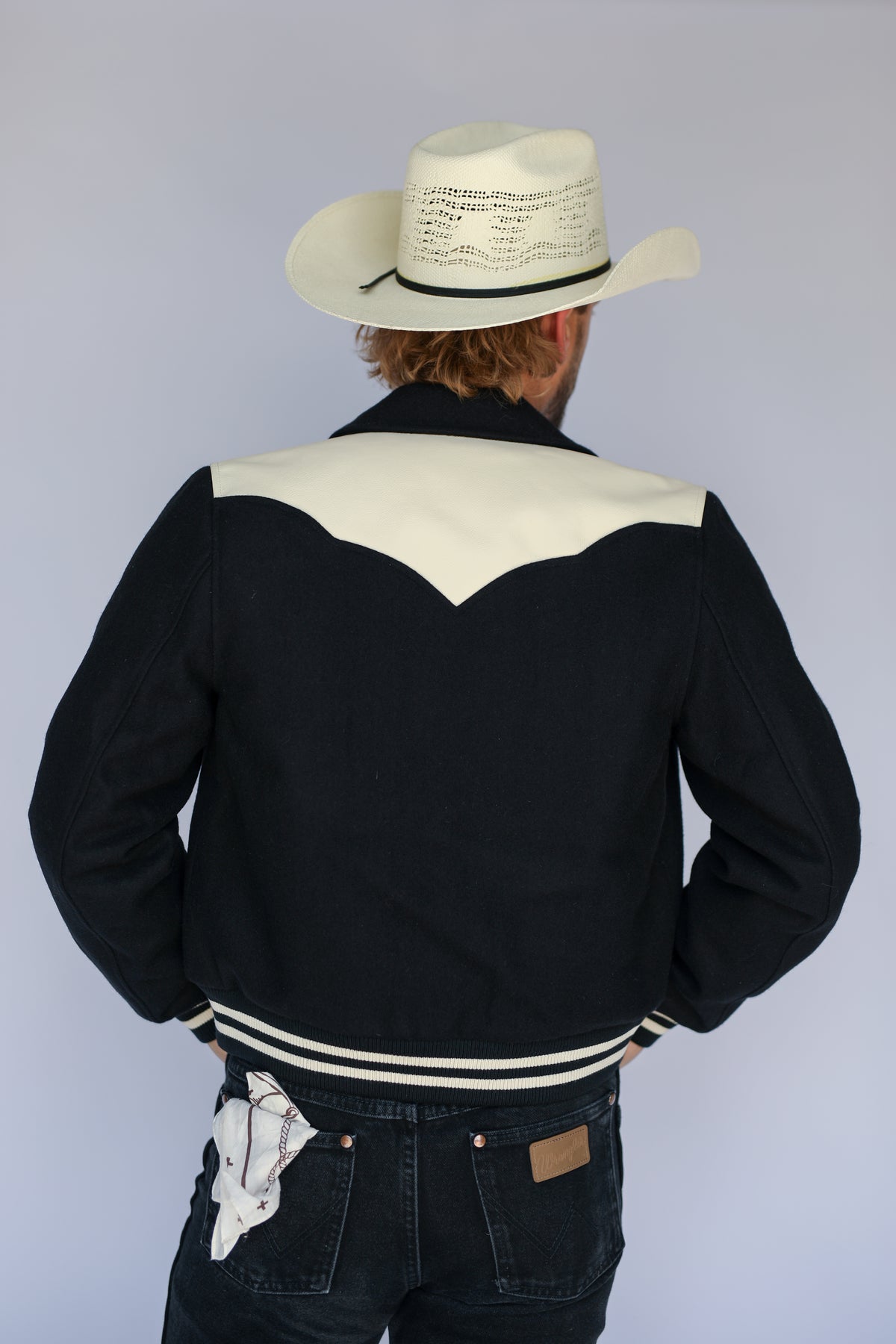 Back view of The Vail unisex black jacket by H Bar C with cream back yoke and striped hem.