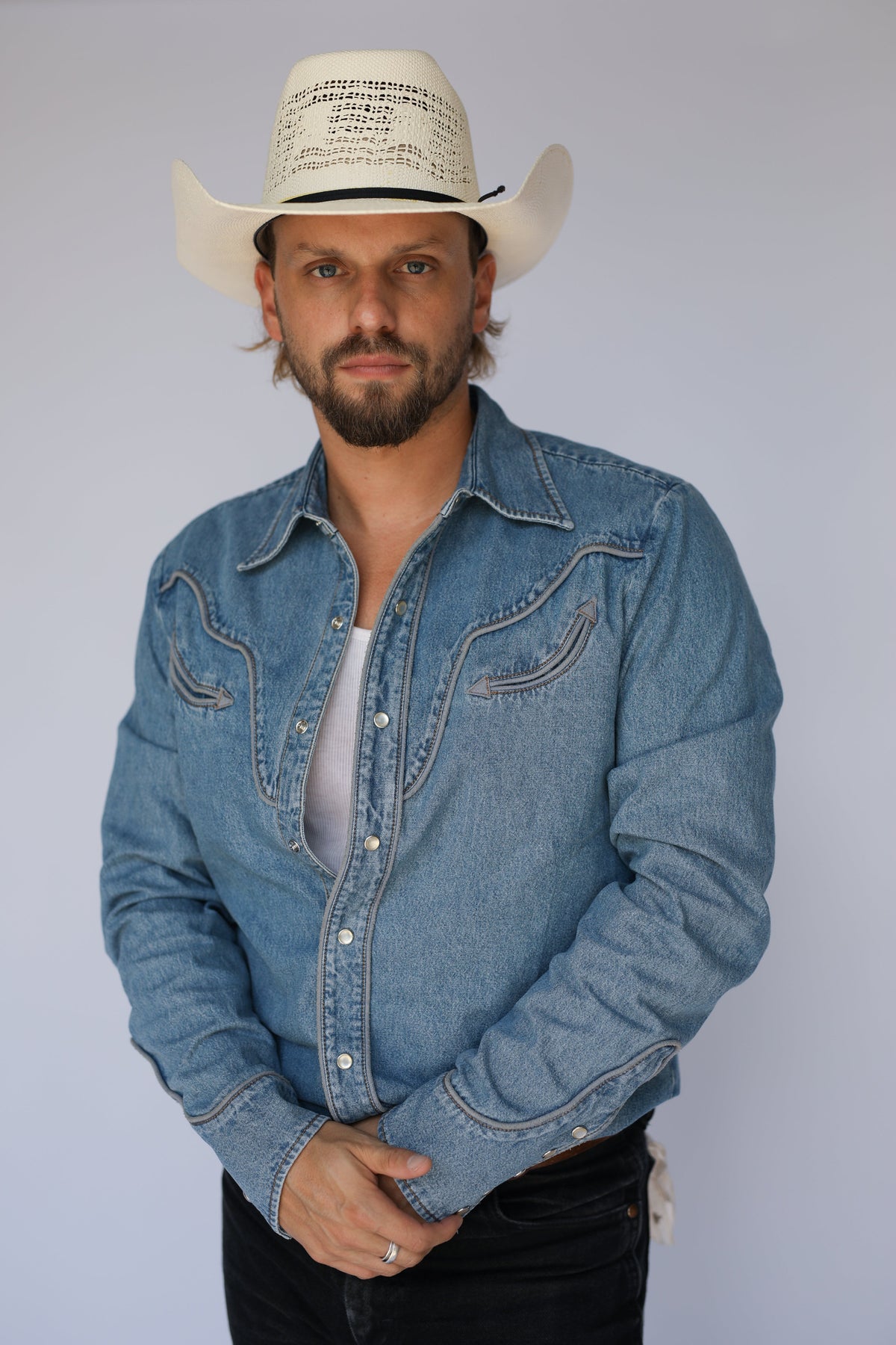 Man in a cream cowboy hat wearing the H Bar C San Fernando men's shirt in light denim with contrast stitching and black jeans.