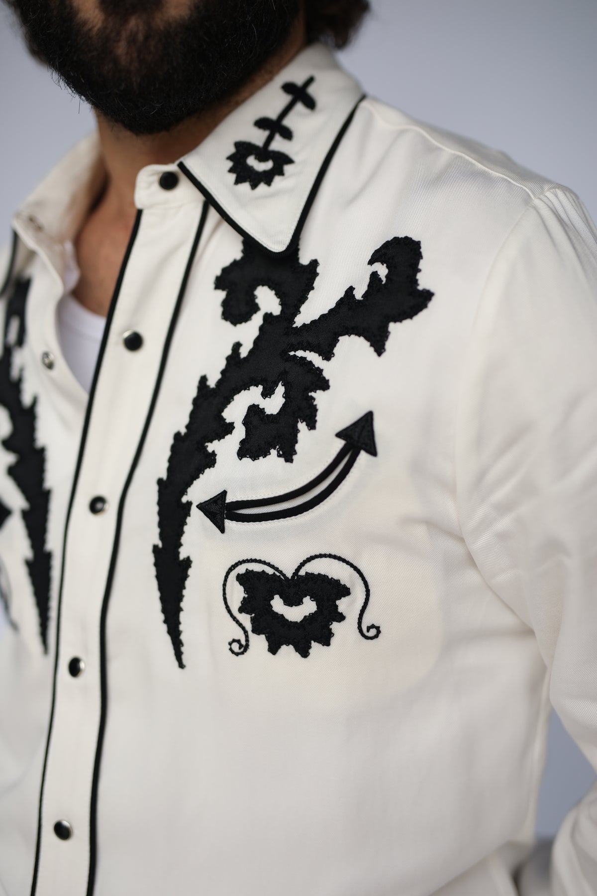 Close-up of the black flame embroidery and arrow on the H Bar C Dali white shirt.