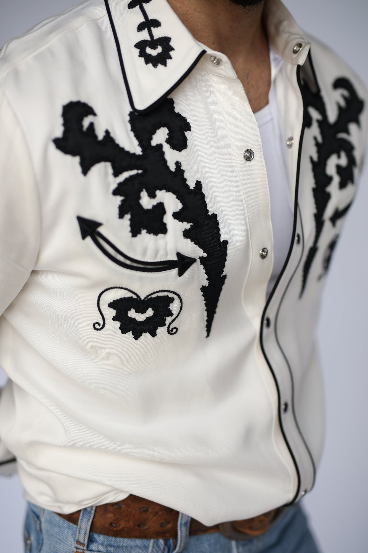 Chest detail of the H Bar C Dali white shirt with black embroidery and piped placket.
