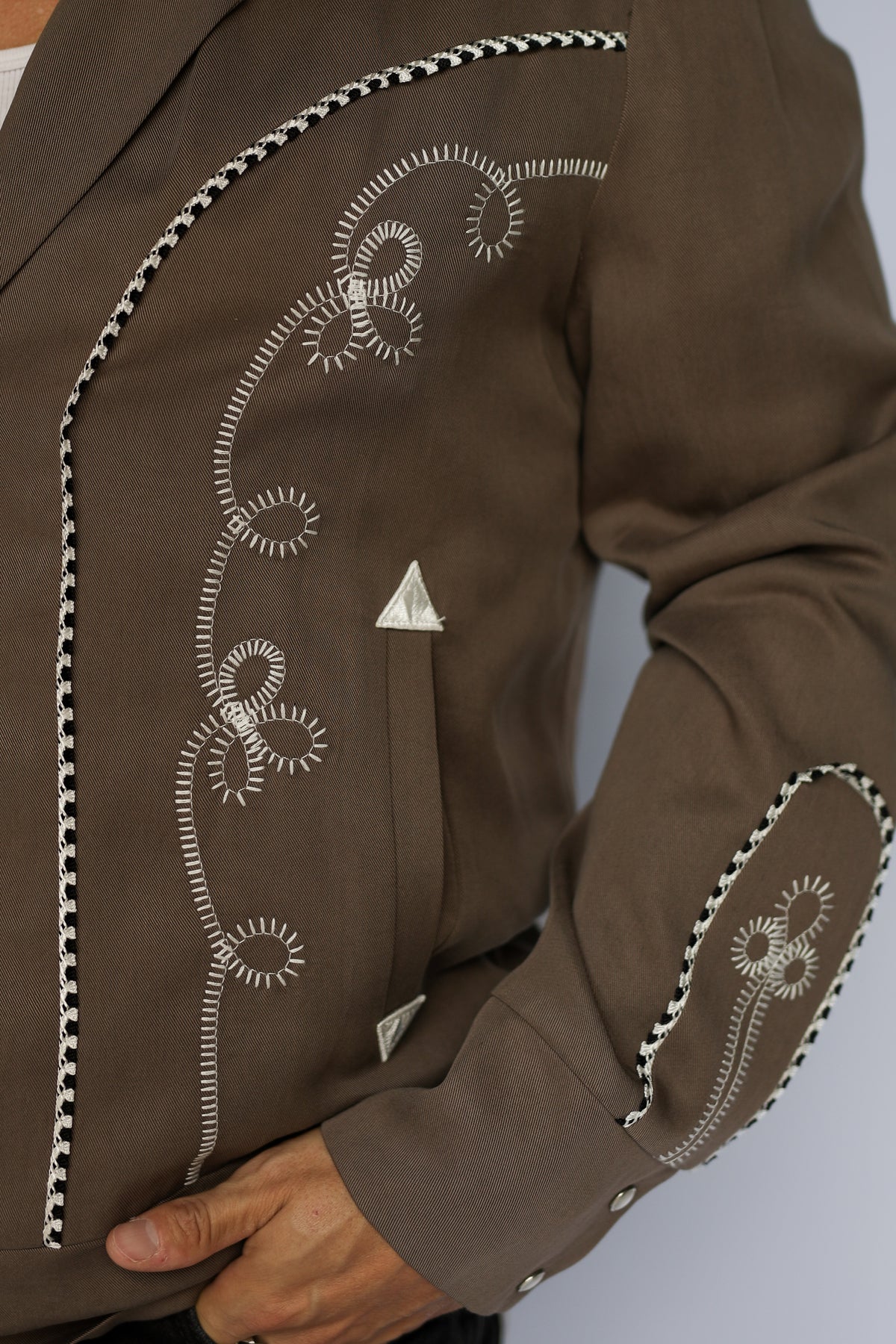 Sleeve and pocket detail of the H Bar C Bolero cocoa and white jacket with white embroidered scrollwork.