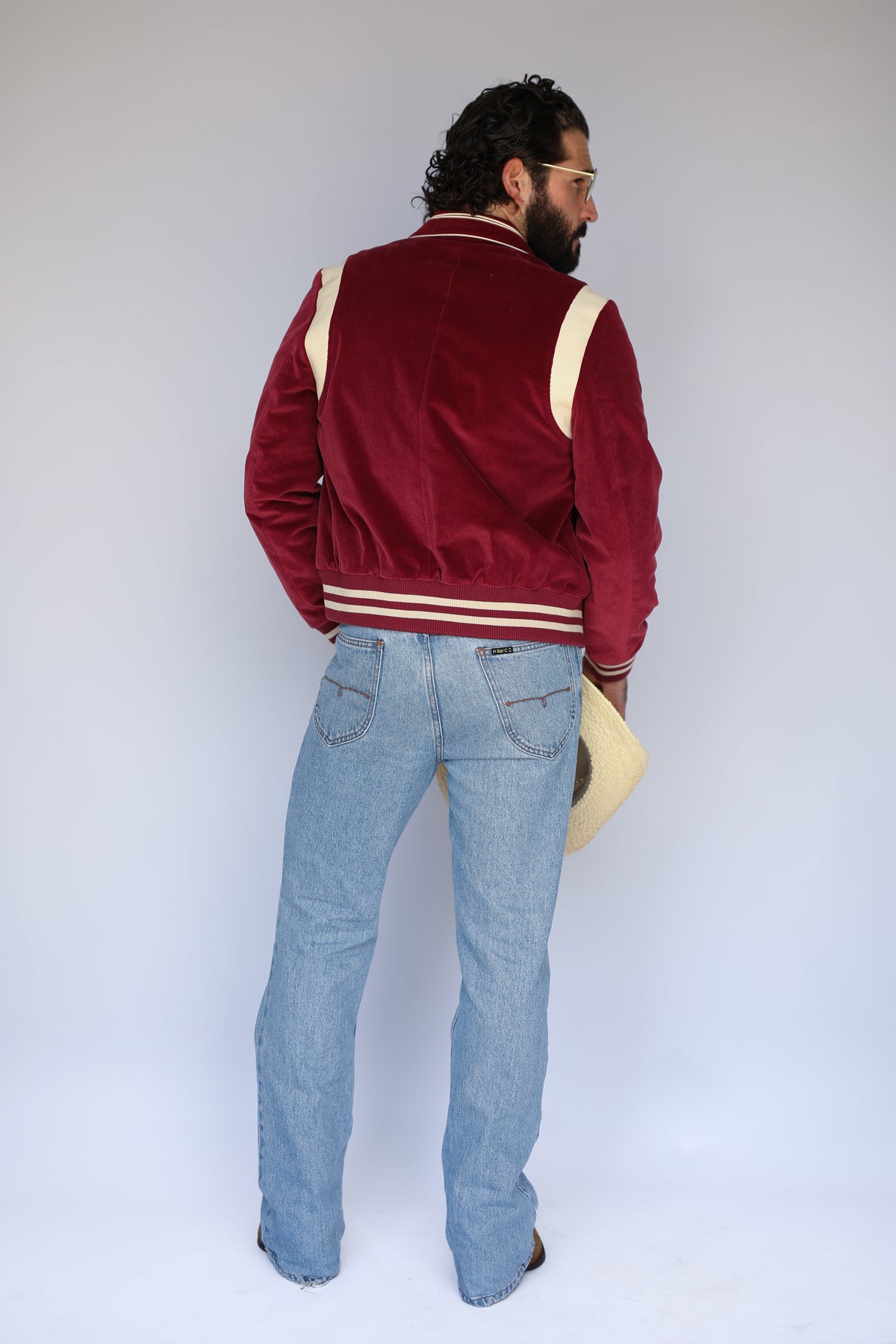 Back view of the H Bar C Silver Lake maroon corduroy jacket with striped ribbed hem and jeans.