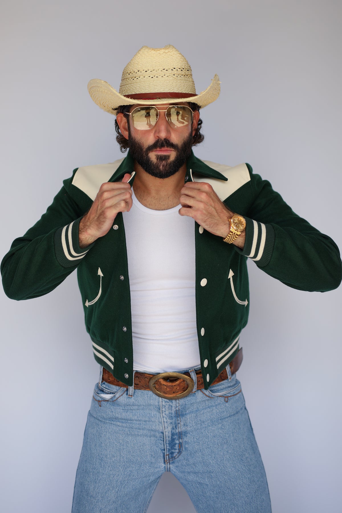 Man holding the collar of The Vail H Bar C green western jacket.