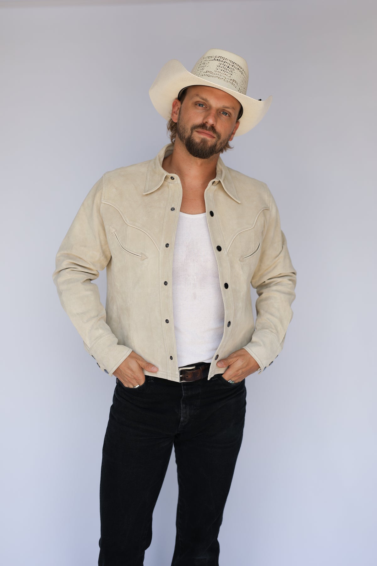 Front view of the H Bar C Austin stone suede jacket worn open over a white tank with black jeans.