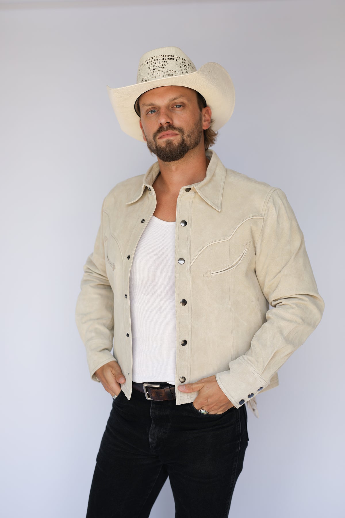 Man wearing the H Bar C Austin stone suede jacket with hands in pockets and a cream hat.