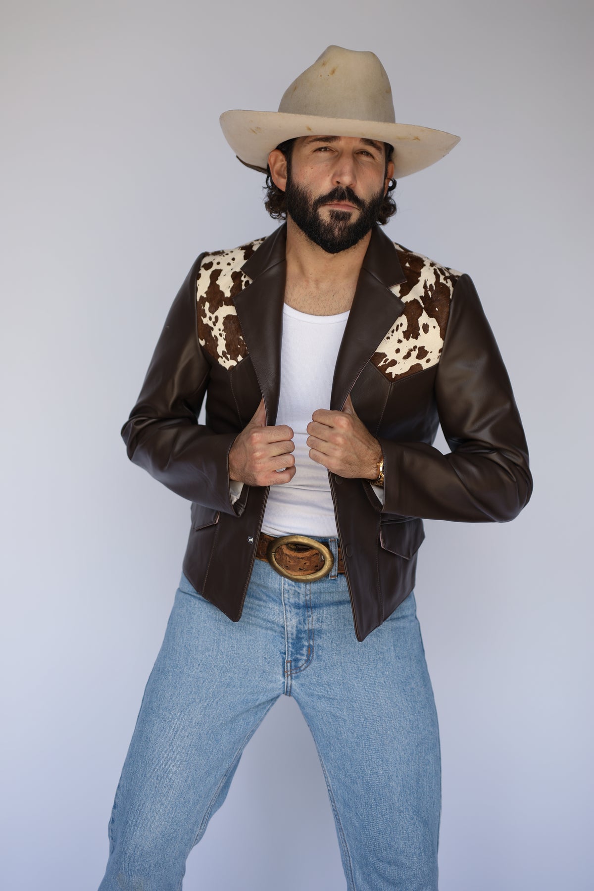 Front view of the H Bar C Cody brown leather jacket with genuine cowhide yoke, white tank and jeans.