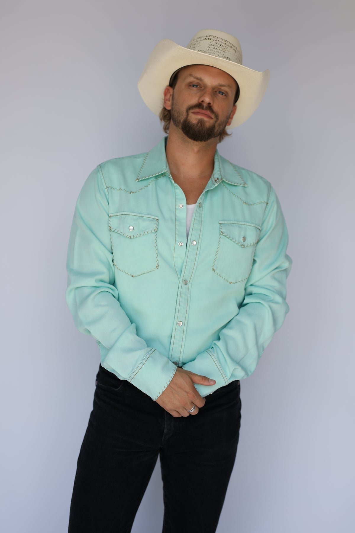 Model in the H Bar C Brooklyn men's turquoise pearl snap shirt with accent stitching around the yokes.