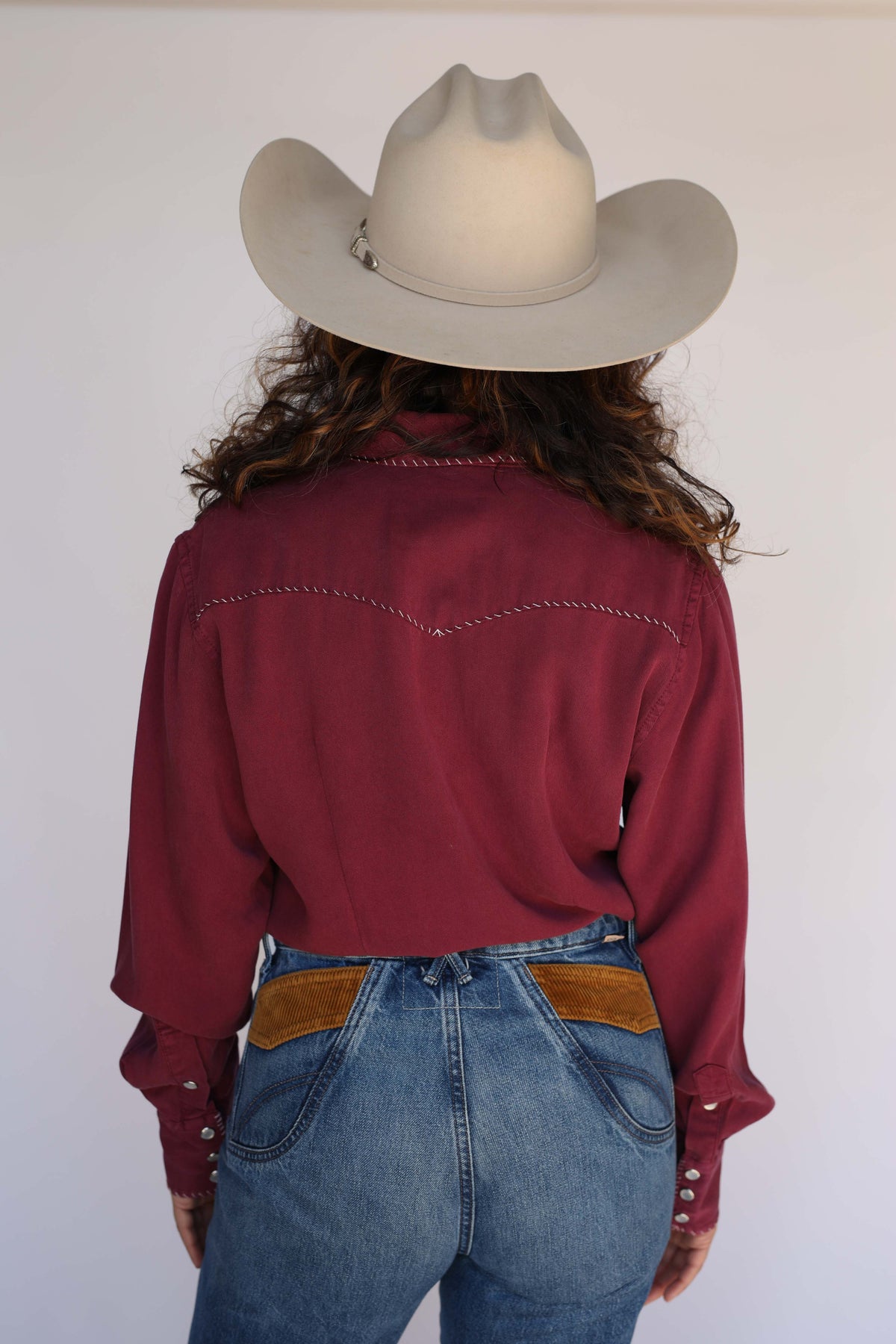 Back view of a woman in a cowboy hat wearing the H Bar C Brooklyn wine shirt.